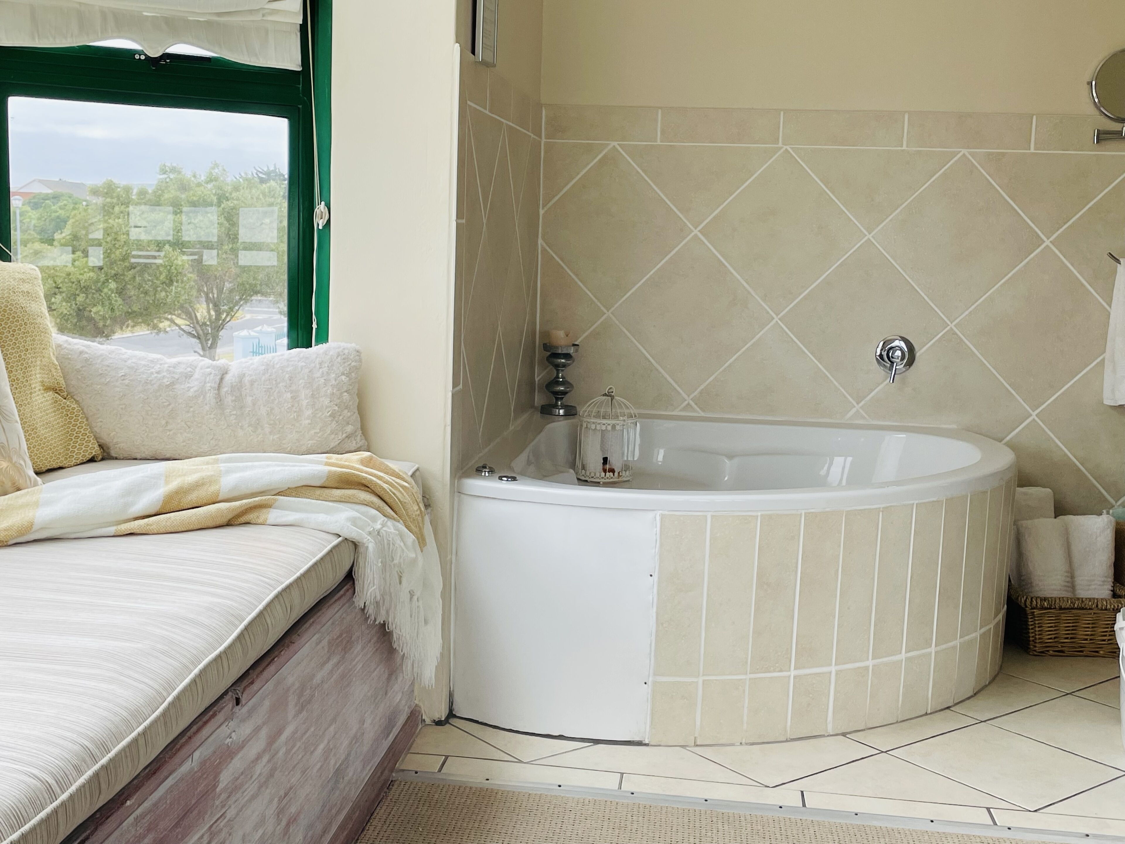 A bathroom with a bathtub, a shower, and a toilet. There is a window with a view of trees and buildings.