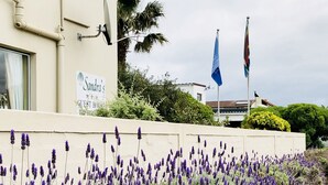 A building with a sign reading "Sandra's Guest House" and flags on a flagpole. - Sandra's Guest House (Langebaan)