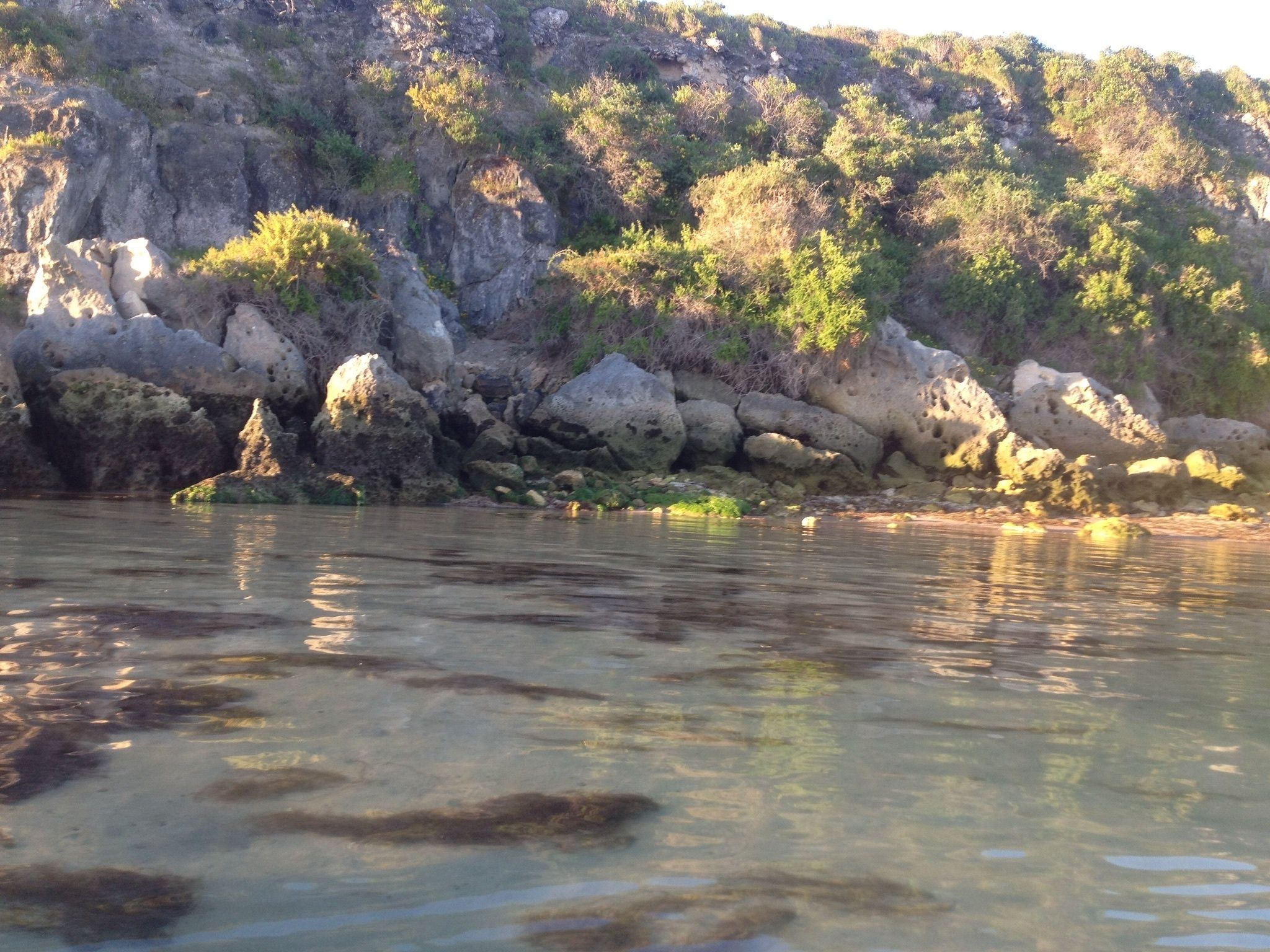 A rocky shoreline with clear water reflecting the surrounding landscape.
