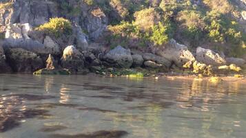 A rocky shoreline with clear water reflecting the surrounding landscape.