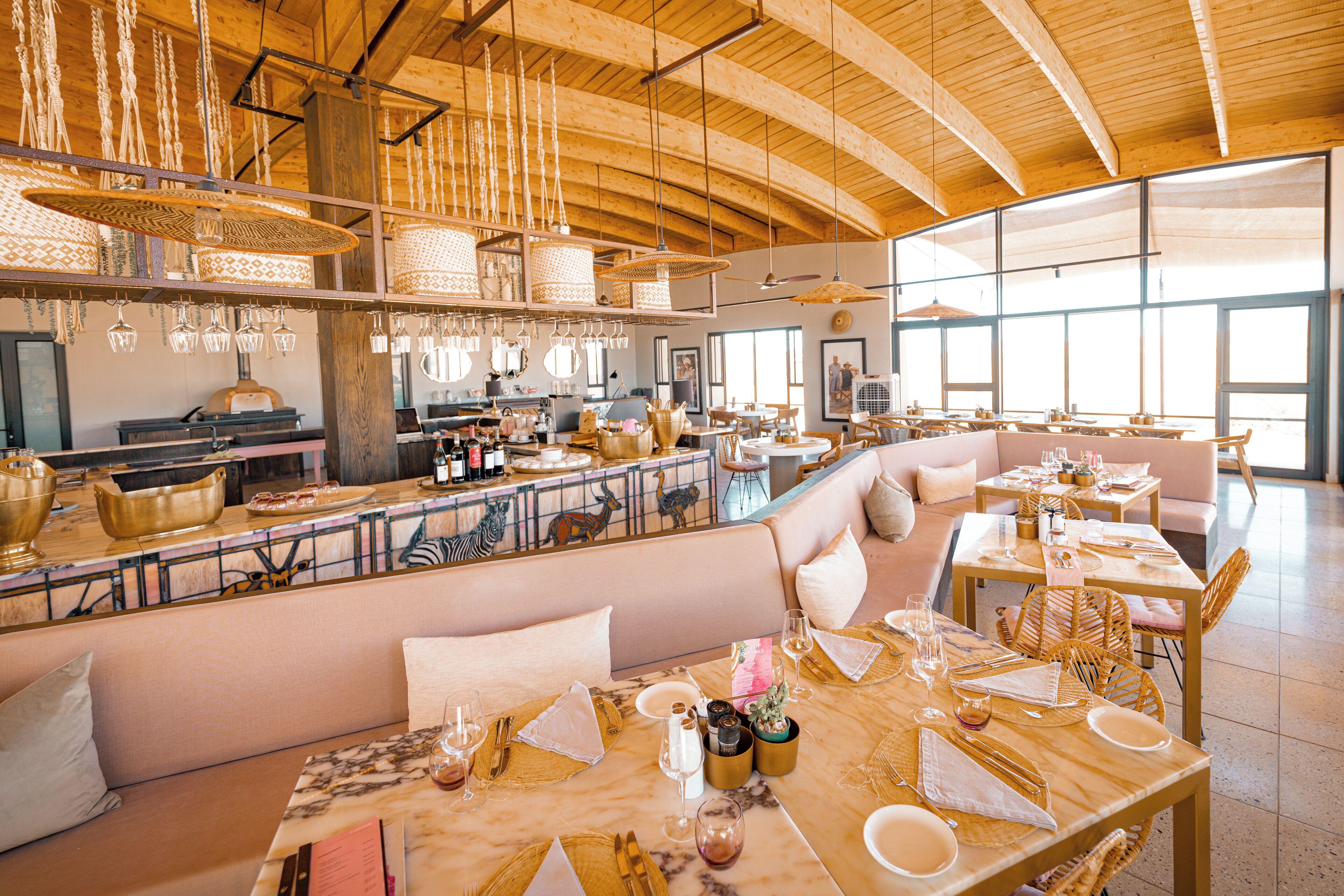 A spacious restaurant with high wooden ceilings, hanging light fixtures, and a variety of seating options including tables and benches.