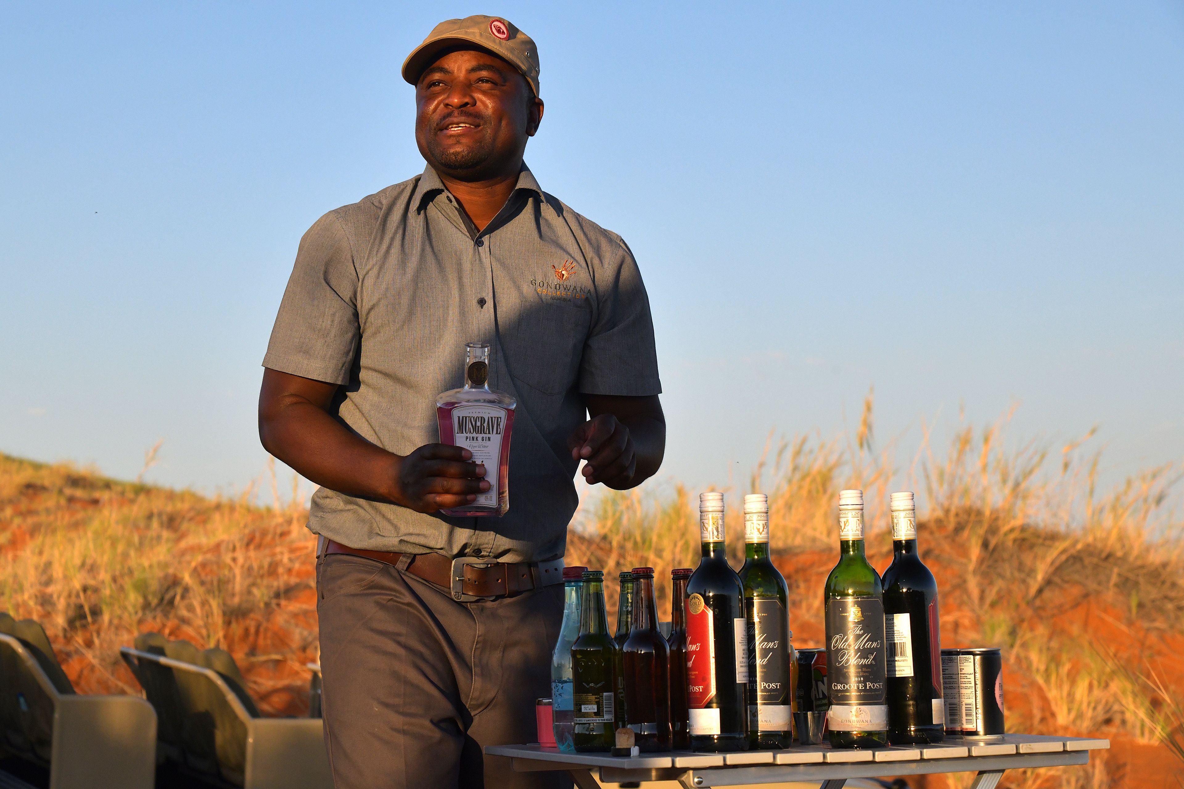 A man holding a bottle of Musgrave wine and standing next to a table with various bottles of wine.