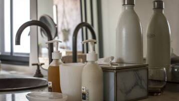 A bathroom counter with a soap dispenser, a lotion bottle, a glass, and a marble box.