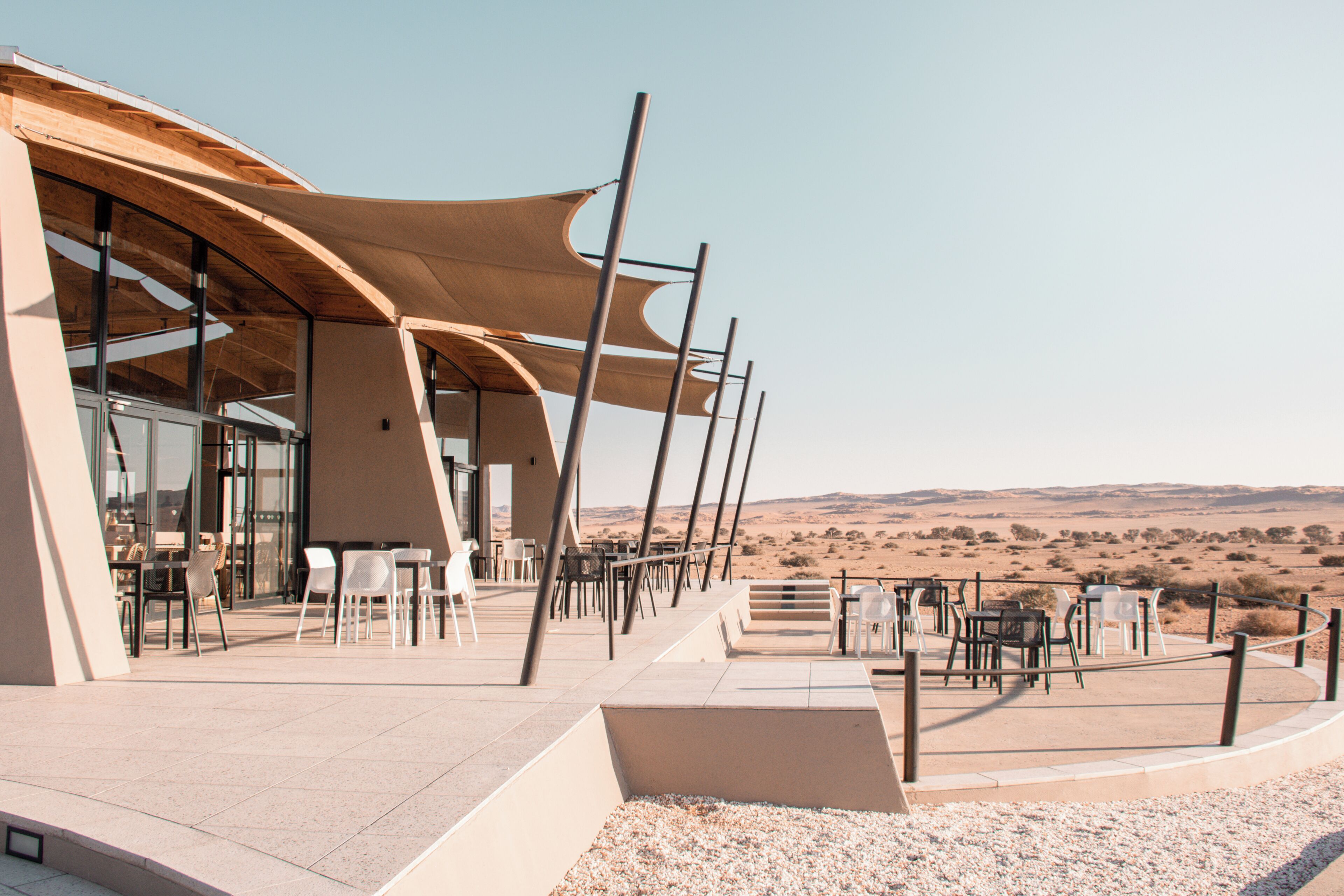 An outdoor dining area with tables and chairs, a covered seating area, and a view of the desert landscape.