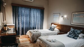 Ein Hotelzimmer mit zwei Betten, einem Schreibtisch und einem Sessel.