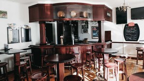 Eine Bar mit Holzhockern, einer Bar und einer Kreidetafel mit der Speisekarte.
