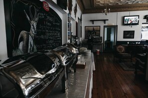 A restaurant interior with a long counter, a chalkboard menu, and a television mounted on the wall. - Karoo Country Inn Hotel (Inxuba Yethemba)