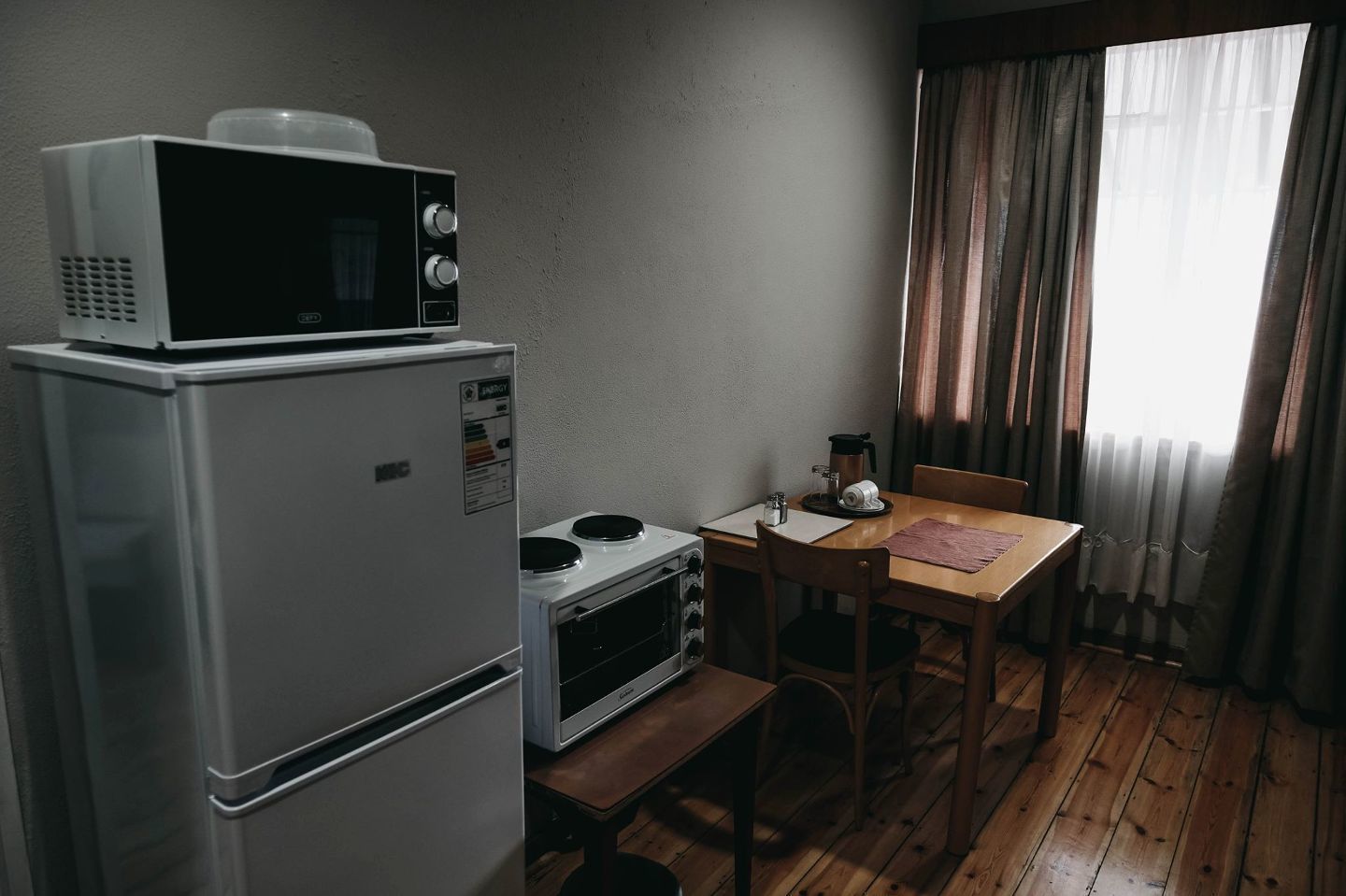 Une petite cuisine équipée d’un micro-ondes, d’un four et d’une machine à café, le tout posé sur une table en bois.