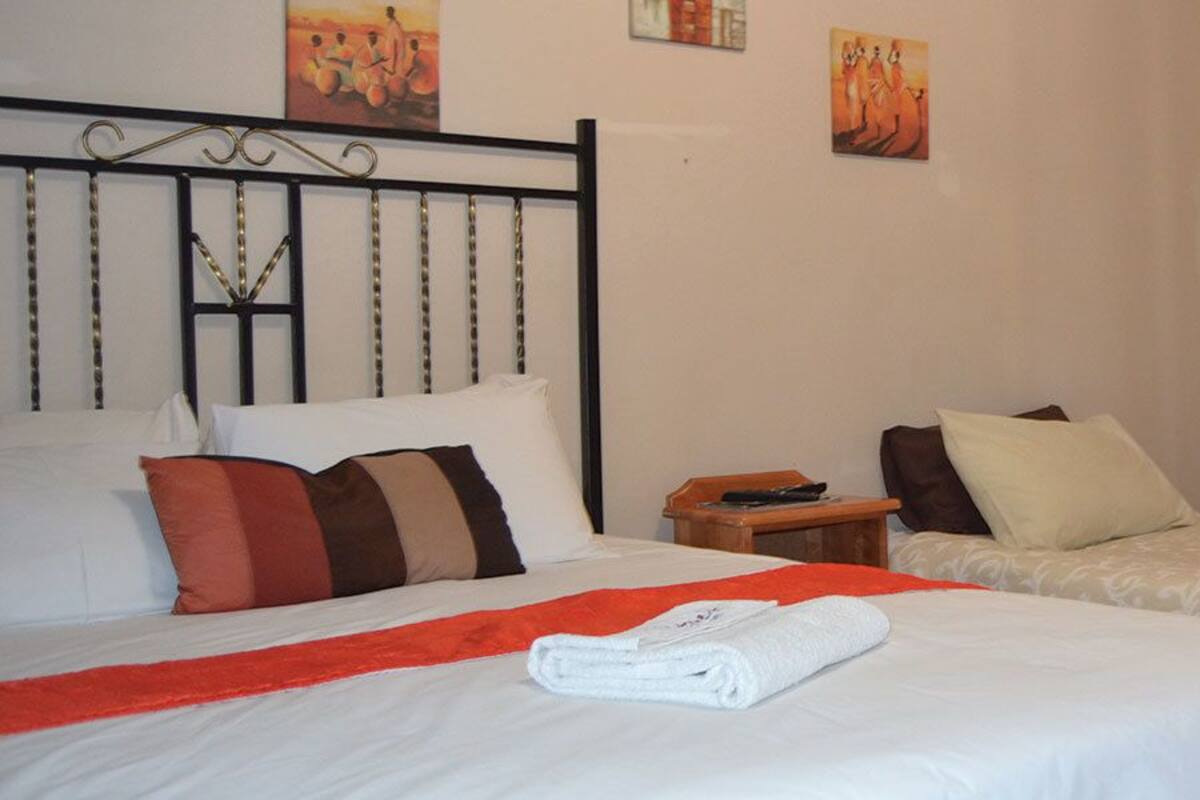 A hotel room with two beds, a wooden nightstand, and a small table with a remote control.