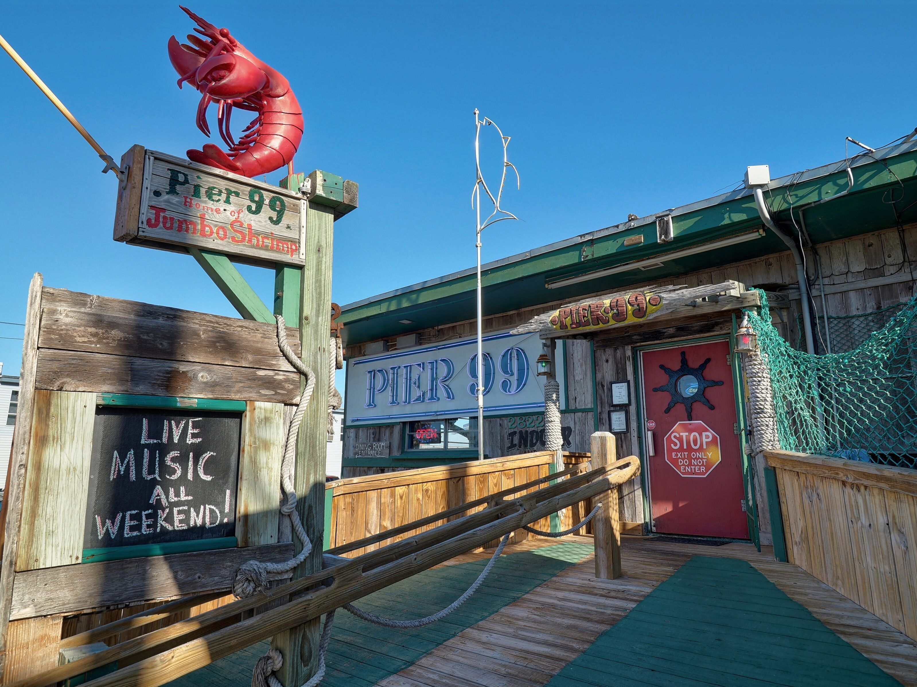 Pier 99 with a lobster sign, a wooden deck, and a sign indicating live music on weekends.