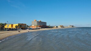 A beachside hotel with multiple floors, a parking lot, and a view of the ocean. - 1st FLOOR LARGE 1BR, BEAUTIFUL Beach Getaway!  Pool, Hot Tub, Sauna & More (Corpus Christi)