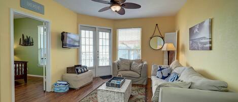 A living room with a ceiling fan, a television, and a couch.