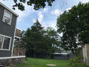 Surrounded by lush trees, this house offers a serene outdoor space with a balcony overlooking the garden.