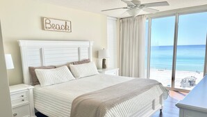 Un dormitorio con una cama grande, un ventilador de techo, vistas a la playa y un cartel que dice "Beach".