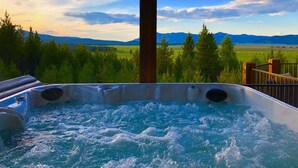 Uma banheira de hidromassagem com vista para uma paisagem montanhosa e um campo.