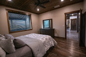 Ein Schlafzimmer mit Bett, Kommode, Deckenventilator und einem Fenster mit Jalousien.