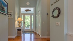 Un corridoio con pavimento in legno, una lampada, un pesce appeso al soffitto e uno specchio al muro.