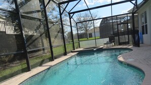 Ein Pool mit Glasüberdachung, umgeben von einer gepflasterten Terrasse und einer Rasenfläche.