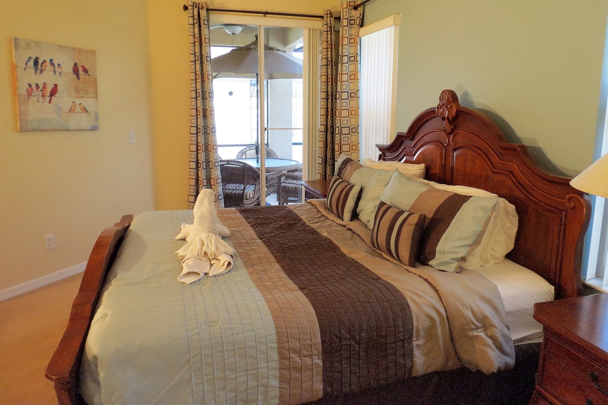 A bedroom with a bed, a wooden headboard, a nightstand, a lamp, and a painting on the wall.
