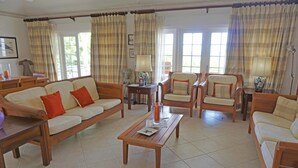 A living room with a sofa, armchairs, a coffee table, and curtains. - Sugar Hill - B8 by Island Villas (Holetown)