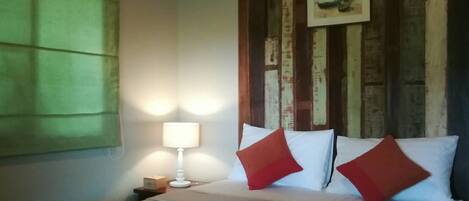 Una habitación de hotel con cama, mesita de noche, lámpara y aire acondicionado.