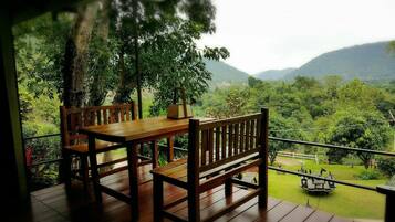 A wooden deck with a table and benches, overlooking a lush green landscape with hills in the distance.