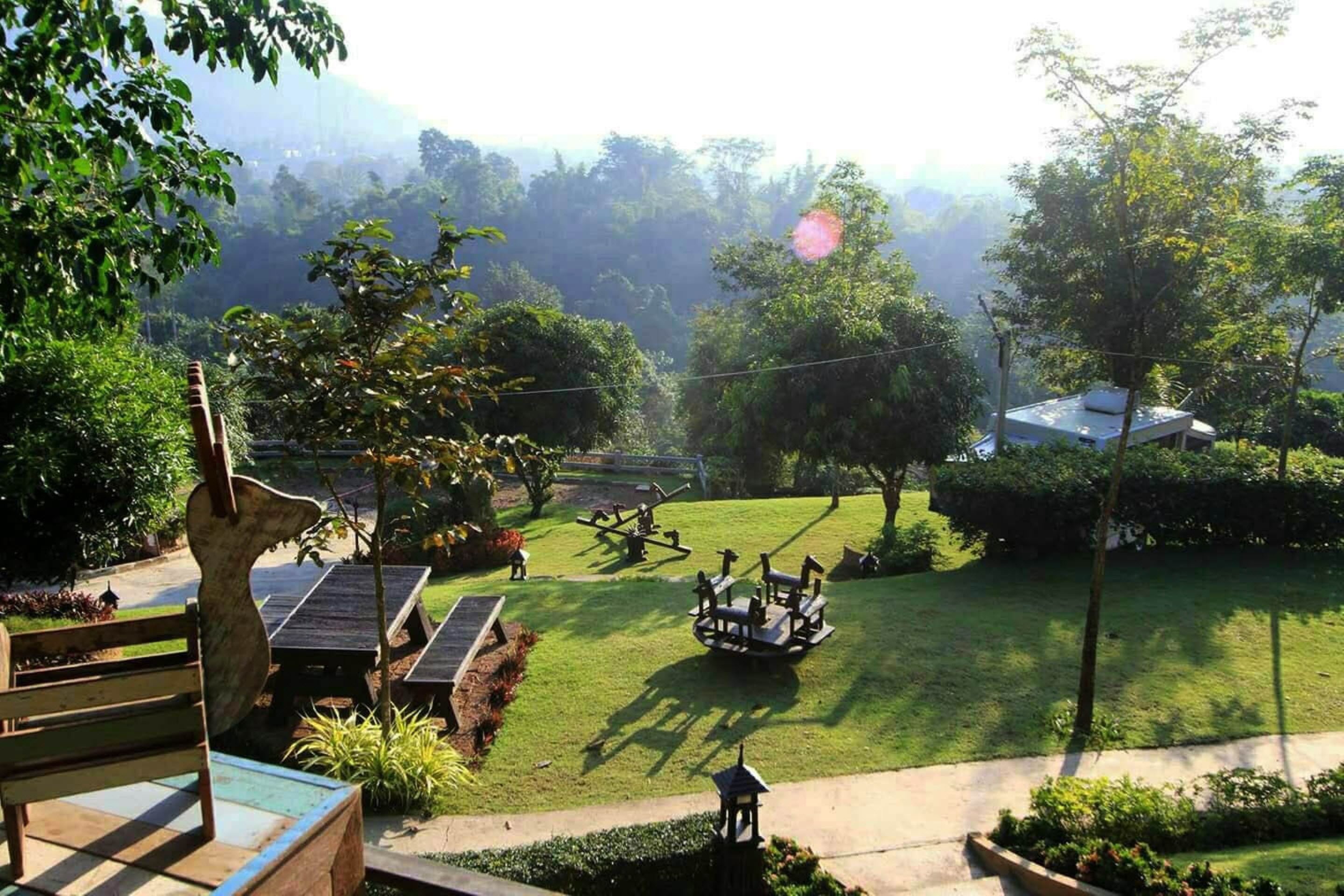 A well-maintained garden with a wooden bench, a small table, and a swing set.