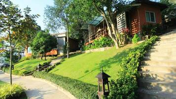 A residential property with a well-maintained lawn, a staircase leading to a wooden deck, and a small garden area.