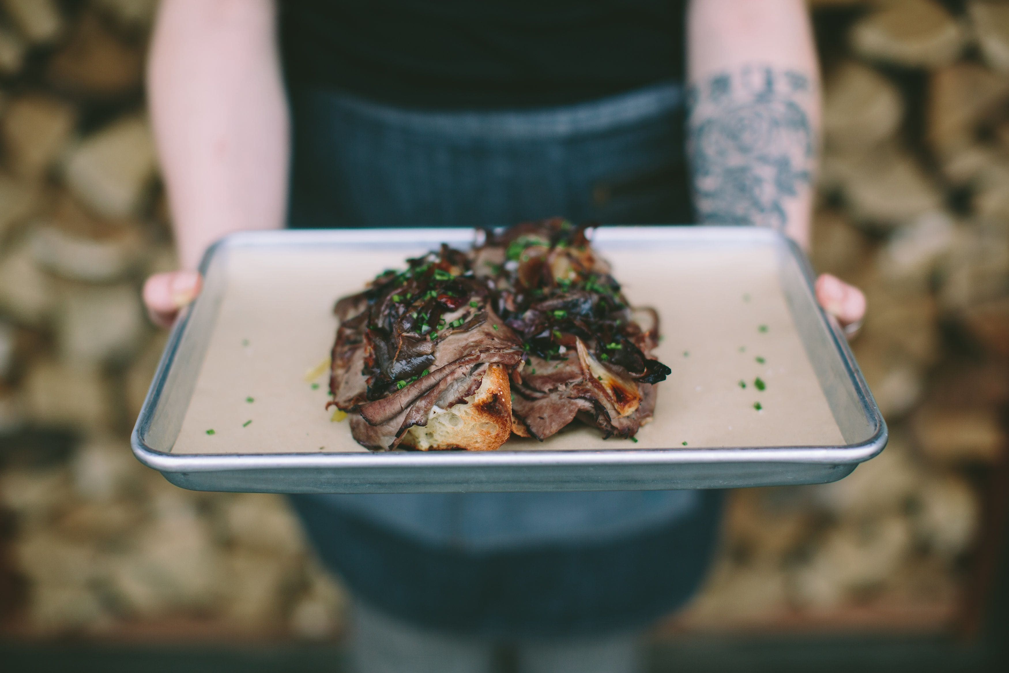 A person holding a tray with a dish of food.