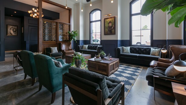 A spacious living room with a large sofa, armchairs, a coffee table, and a chandelier.