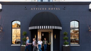 The Atticus Hotel entrance with a dark facade, arched windows, and a sign above the door.