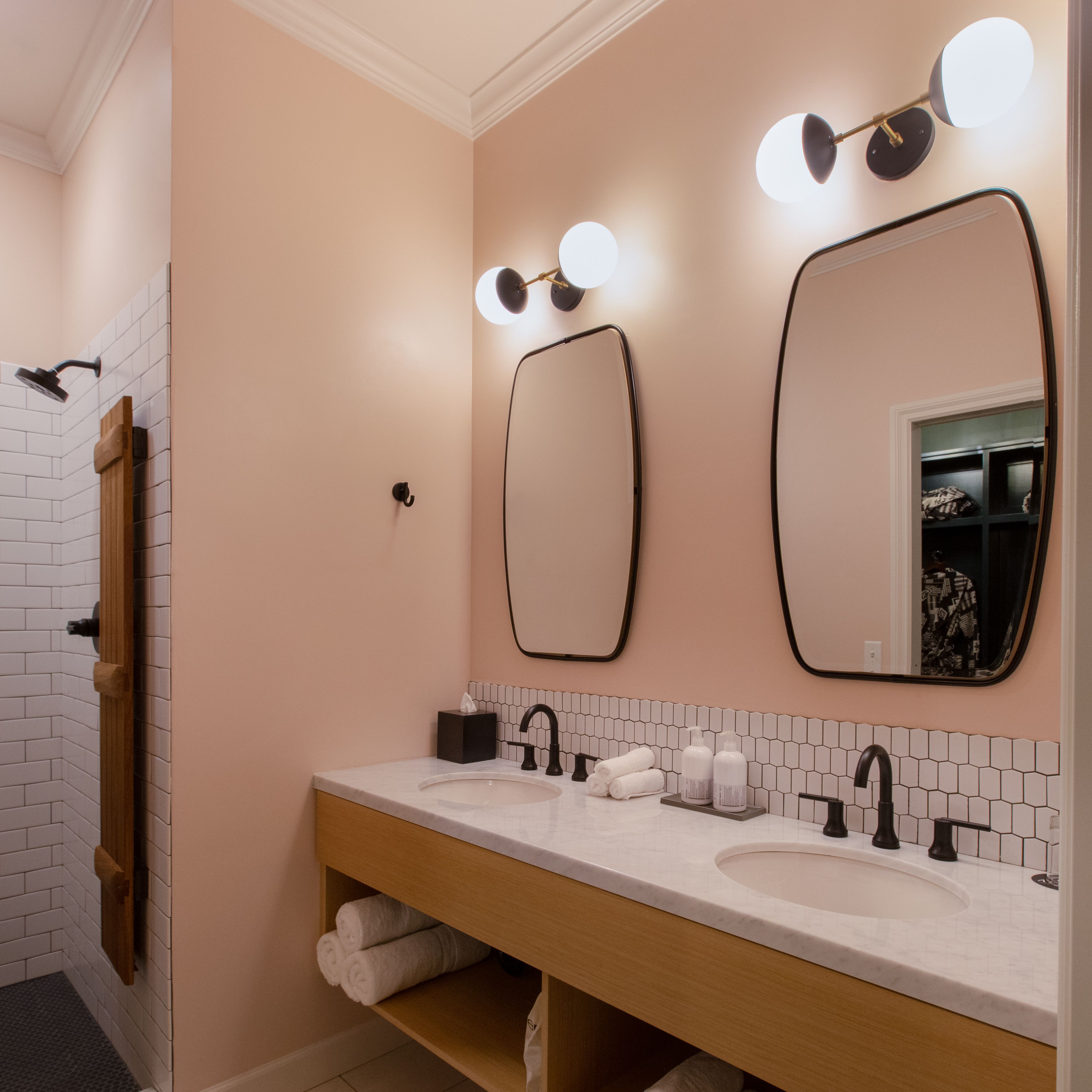 A bathroom with a double sink, a mirror, and a towel rack.
