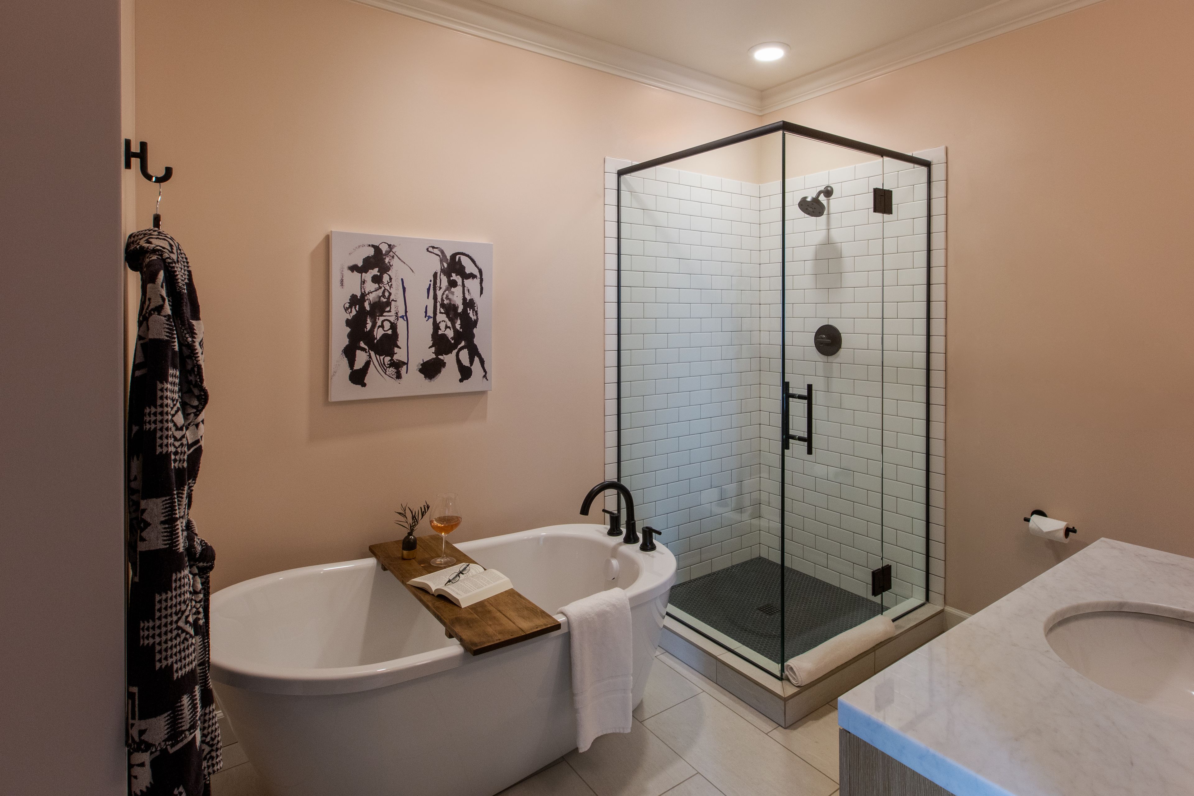 A modern bathroom with a freestanding bathtub, a glass-enclosed shower, and a marble sink.