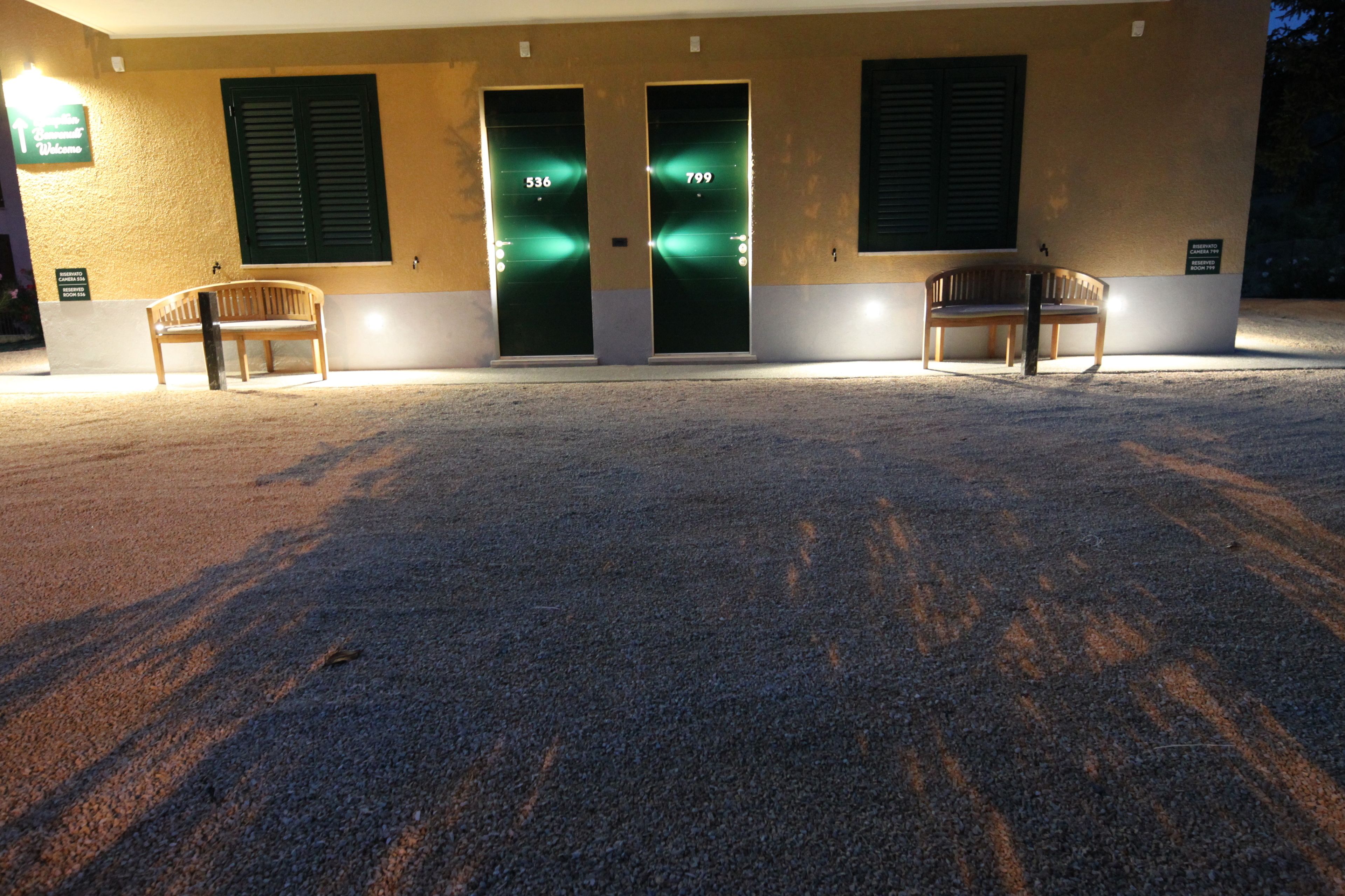 A building with two doors marked 536 and 799, a bench, and a sign indicating a welcome area.