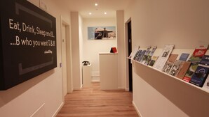 Un pasillo con un cartel de motivación a la izquierda, un escritorio pequeño con un teléfono y una exhibición de folletos a la derecha.