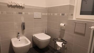 Ein modernes Badezimmer mit integriertem Bidet, Toilette und Handtuchhalter.