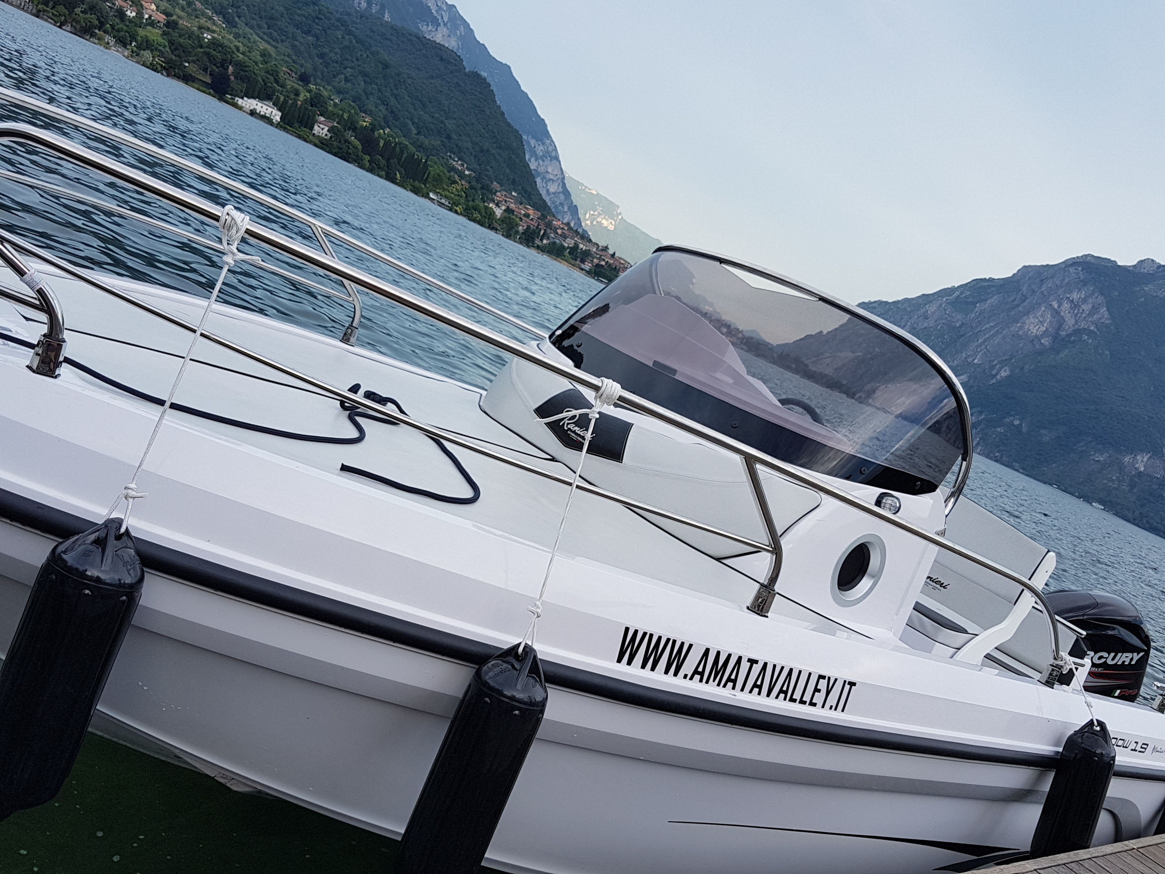 Ein Boot liegt an einem Steg in einer Marina vor einer Bergkulisse.