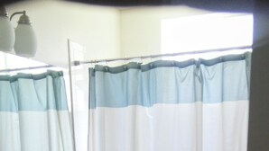 Un bagno con tenda da doccia a righe, un water e un mobile lavabo con specchio.