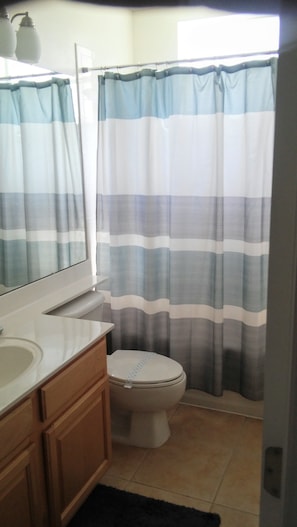 A bathroom with a striped shower curtain, a toilet, and a vanity with a mirror.
