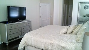 Una camera da letto con un letto, una cassettiera, una televisione e una porta.