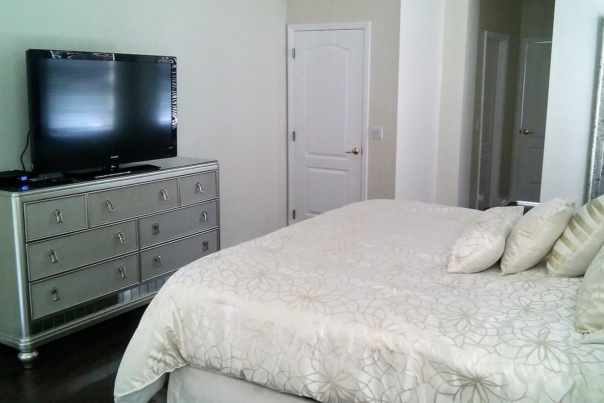 Une chambre à coucher avec un lit, une commode, une télévision et une porte.