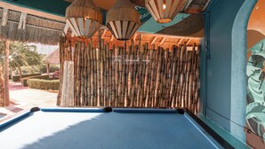 Une table de billard avec un fond en bambou et des lampes suspendues.