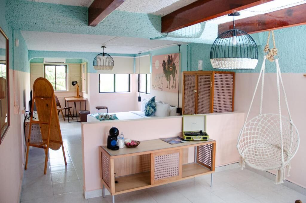 A room with a wooden desk, a hanging chair, and a bed.