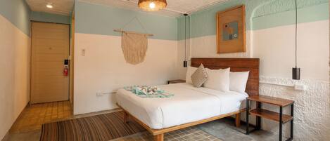 Une chambre à coucher avec un lit, une table de chevet, une décoration murale en macramé, une tête de lit en bois et un tapis à motifs.