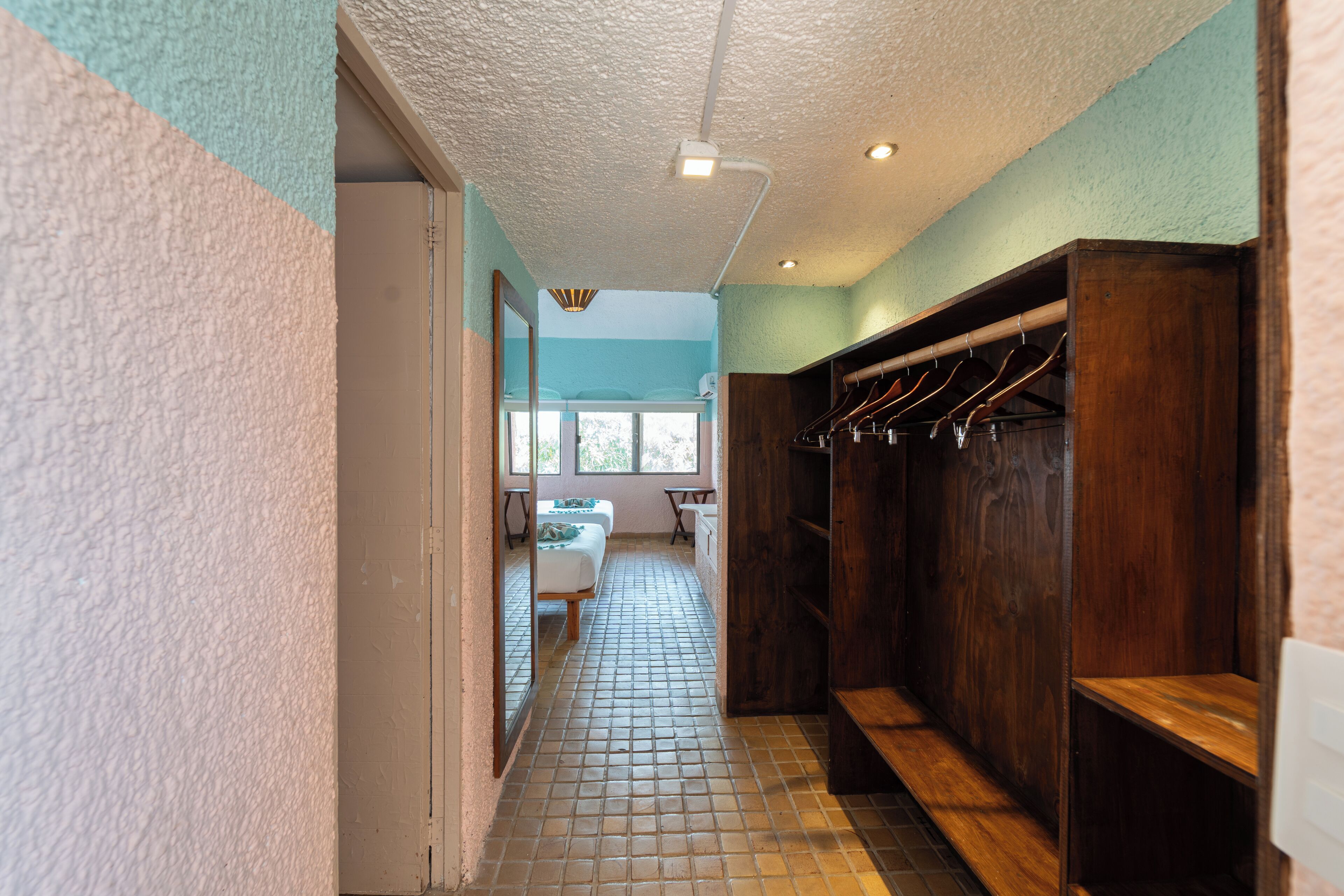 A hallway with a tiled floor, a wooden bench, and a coat rack.