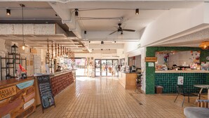 Un espace intérieur spacieux comprenant un comptoir, des étagères et un mur végétal orné de panneaux affichant le menu.