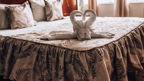A neatly made bed with a floral bedspread, a painting on the wall, and a window with curtains. - Casa Baraquel (Arequipa)