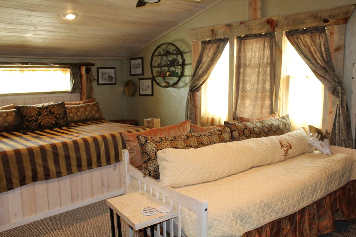 A cozy room with two beds, a small table, and a window with curtains.