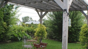A wooden pergola with a table and two chairs in a garden. - Amie St.Jéan Bed and Breakfast (Rapid City)