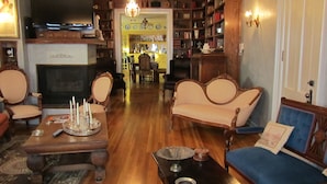 A traditional living room with a fireplace, wooden furniture, and a bookshelf filled with books and decorative items. - Amie St.Jéan Bed and Breakfast (Rapid City)